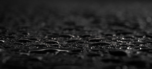 Dark gray black slate background with water drops or natural stone texture. Black board for serving close-up. Drops of water close-up on a black background