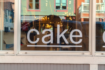 Fototapeta na wymiar Close up of a white cake sign on the shiny glass window of a store building