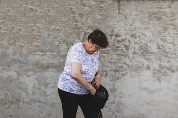 Angry retired lady looking and seeking something in her purse