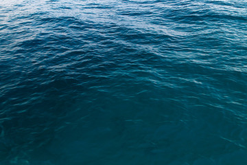 Clear water texture in blue. Background of the ocean and the sea backlit by the sun.