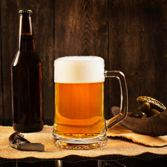 Pint of beer with bottle on rustic wooden background