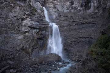 Large waterfall between stone walls.