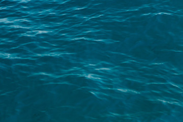 Clear water texture in blue. Background of the ocean and the sea backlit by the sun.