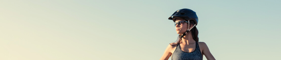 Girl on a mountain bike on offroad, beautiful portrait of a cyclist at sunset, Fitness girl rides a...