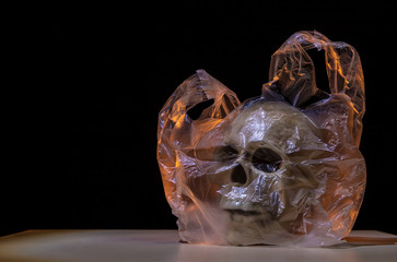 A plastic bag is on a table. Inside is a skull as a symbol of pollution. Concept: environmental...