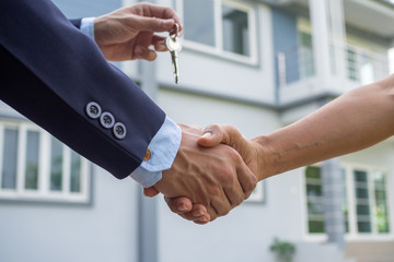 Agent sells the house shake hand with the buyer and send house key to the buyer.