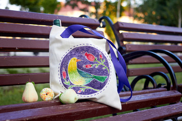 White linen eco bag decorated with painting of birds and flowers on the bench