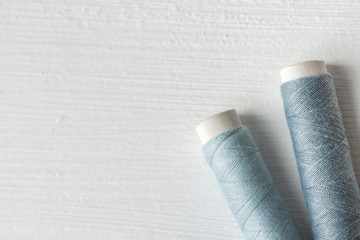 Sewing gray threads on cardboard spools on white painted wood background. Crafts hobbies local artisan business concept. Clean minimalist style copy space