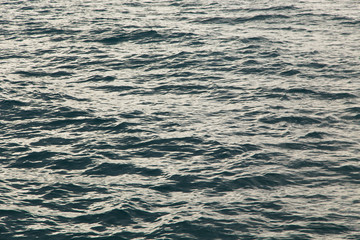 Clear water texture in blue. Background of the ocean and the sea backlit by the sun.