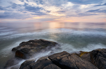 Scenic sunset over water seen from rocky shore, long time exposure, Sri Lanka West Coast.