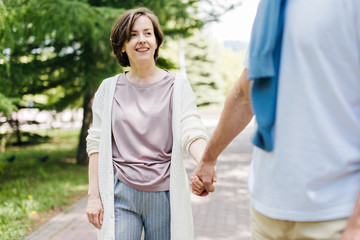 Naklejka premium Middle-aged married couple walking in the park holding hands.
