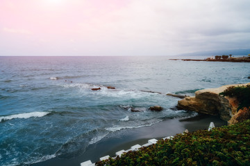 Beautiful seascape in cloudy weather. Light waves on the black sand beach.