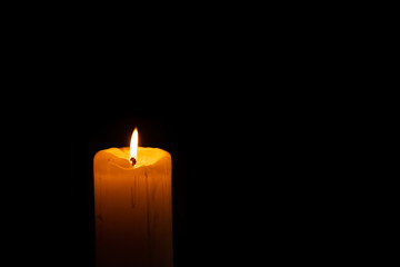 a single burning candle in the dark