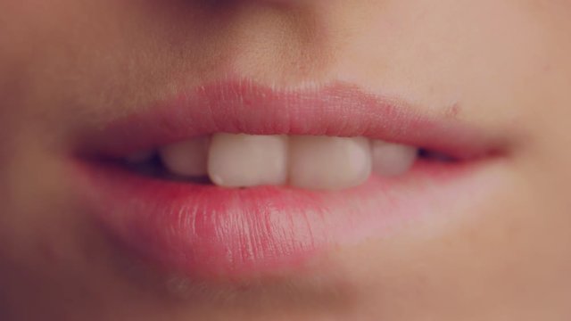 Macro shot of sexy woman playing and bites on her red lips, slow motion