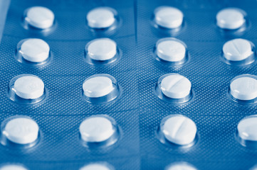 White tablets, pills in green blister pack. Medicament treatment. Health care photo.  toned  in classic blue trendy color of the year 2020