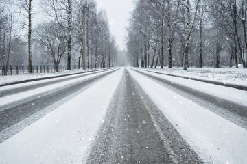 Fototapeta na wymiar Winter country road in snowfall. Wheel tracks on a snowy road
