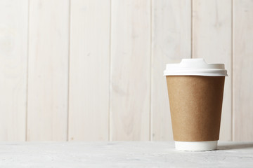 Paper cup of coffee on table on bright background