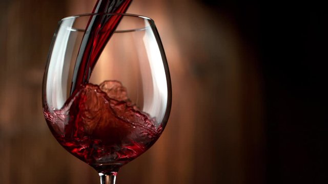 Super Slow Motion Detail Shot of Pouring Red Wine on Wooden Background at 1000fps.