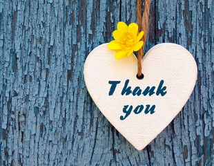 Thank You or thanks greeting card with yellow flower and decorative white heart on blue wooden background.International Thank You Day concept.Selective focus.
