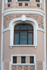 Fragment of the facade of an old building with a window framed by a twisted floral pattern