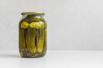 Fermented vegetables. Glass jar with homemade pickled ugly cucumbers on a white background. Copy space, close-up