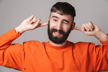 Image of bearded man with nose jewelry smiling and plugging his ears