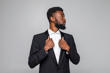 Successful young african businessman in suit standing over gray background