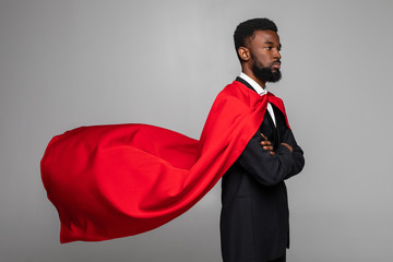 Side view of african businessman in suit with hero red cout isolated on gray background
