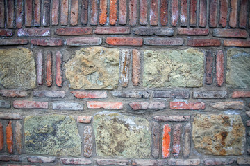The surface of the ancient wall of red decorative bricks and stones. Georgia