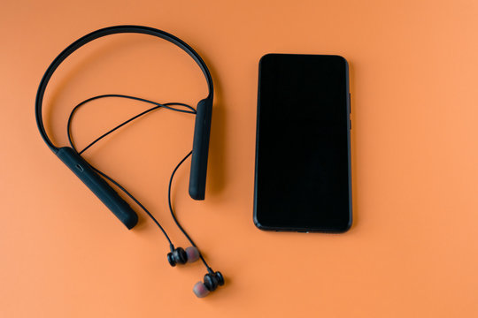 Black wireless bluetooth headphones for the phone on an orange background. Headset for the phone..