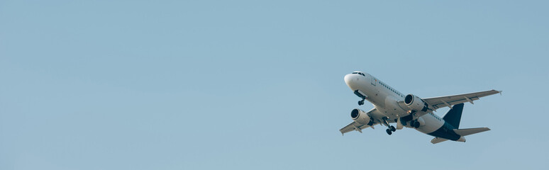 Panoramic shot of jet plane taking off in blue sky with copy space