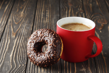 Cup with coffee and sweet tasty donut on a rustic table with place for text.