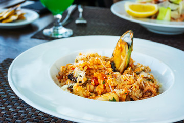 Tasty risotto with Shrimp, fresh herbs vegetables on a white plate