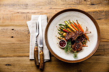 Grilled Venison Ribs with baked vegetables and berry sauce on wooden background