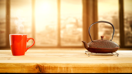 Desk of free space for your decoration and window sill with city landscape.Hot tea and kettle. Sun light and morning time. 