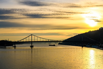Sunrise over Dnipro Dnieper River embankment in Kyiv. Pedestrian bridge on the background. Kyiv, Ukraine. December 2019