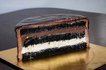 A half of chocolate cake with black glaze on a black table. Picture for a menu or a confectionery catalog.