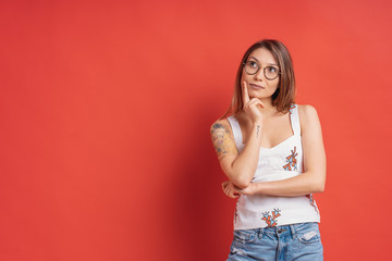 Caucasian woman with glasses thinking and imagination isolated on red background