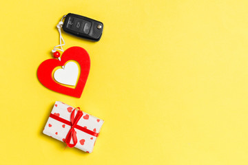 Top view of gift box, car key and wooden heart on colorful background. Luxury present for Valentine's day