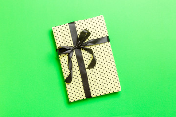 Top view Christmas present box with black bow on green background with copy space