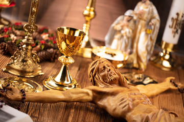 Catholic concept background.  The Cross, monstrance, Jesus figure, Holy Bible and golden chalice on the rustic wooden table.