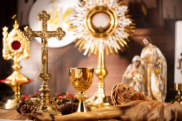Catholic concept background.  The Cross, monstrance, Jesus figure, Holy Bible and golden chalice on the rustic wooden table.