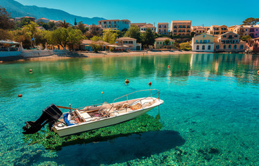 Wonderful Sunny seascape of Asos village, Kefalonia Island. Greece. Sunny spring seascape. boat in azure clear Water of Ionian Sea under sunlit. Beautiful landscape with bay and colorful buildings