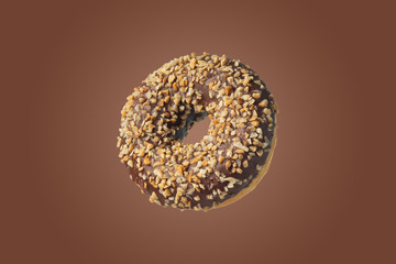 Chocolate donut with nuts on a brown background.