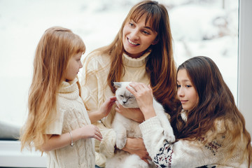 Beautiful mother with children. Family at home. People sitting near winter windows