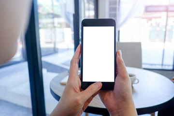 Mockup picture of business man's hands or woman’s hands holding smart phone with white blank screen in modern place.