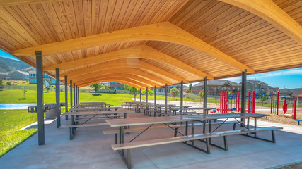 Pano Park pavilion playground and basketball court gainst homes mountain and blue sky