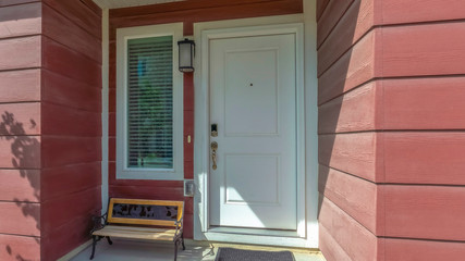 Pano Close up of townhouse facade with a bench by the white front door and window