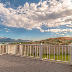 Square Back porch of a home with view of lake and mountain under cloudy blue sky
