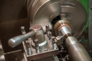 Close-up scene of lathe machine cutting the metal shaft parts. The standard turning machine operation with metal shaft parts.